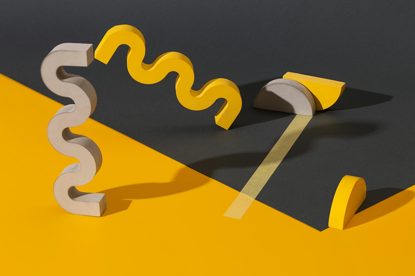 Grey and yellow geometric shapes arranged on a two-toned surface.