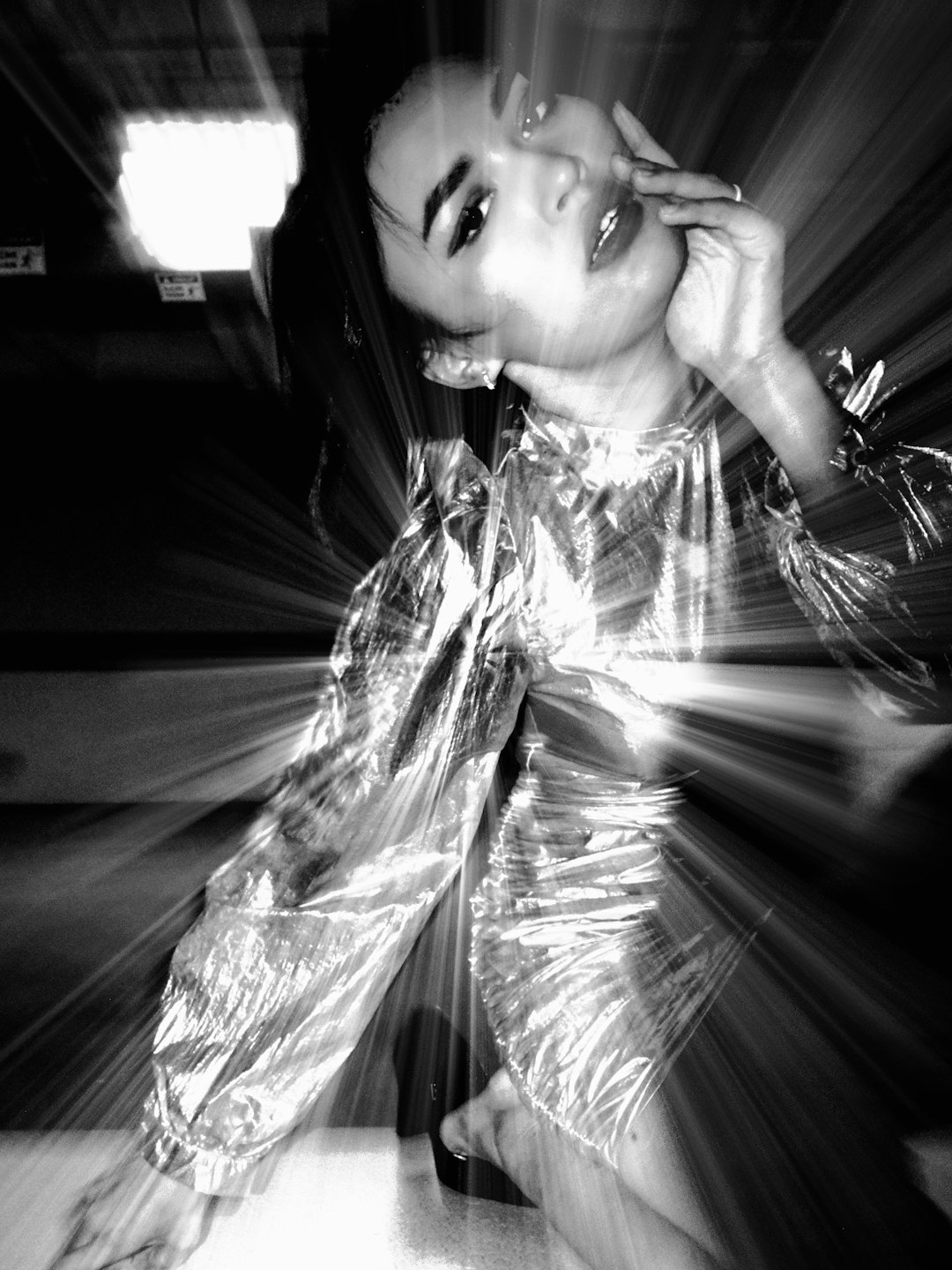 Woman in a reflective dress posing with her hand near face.